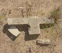 A broken cement cross in Valley Wells Cemetery